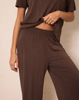 A person wearing a matching brown lounge set consisting of a short-sleeve top and high-waisted, wide-leg pants with an elastic waistband, shown against a plain beige background.
