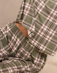 A close-up of a plaid pajama set with an olive green, cream, and burgundy check pattern, featuring a long-sleeve top and matching pants.