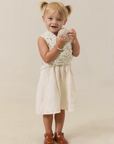 Young girl in a white dress wearing a strawberry solly dolly carrying a stuffy on beige background