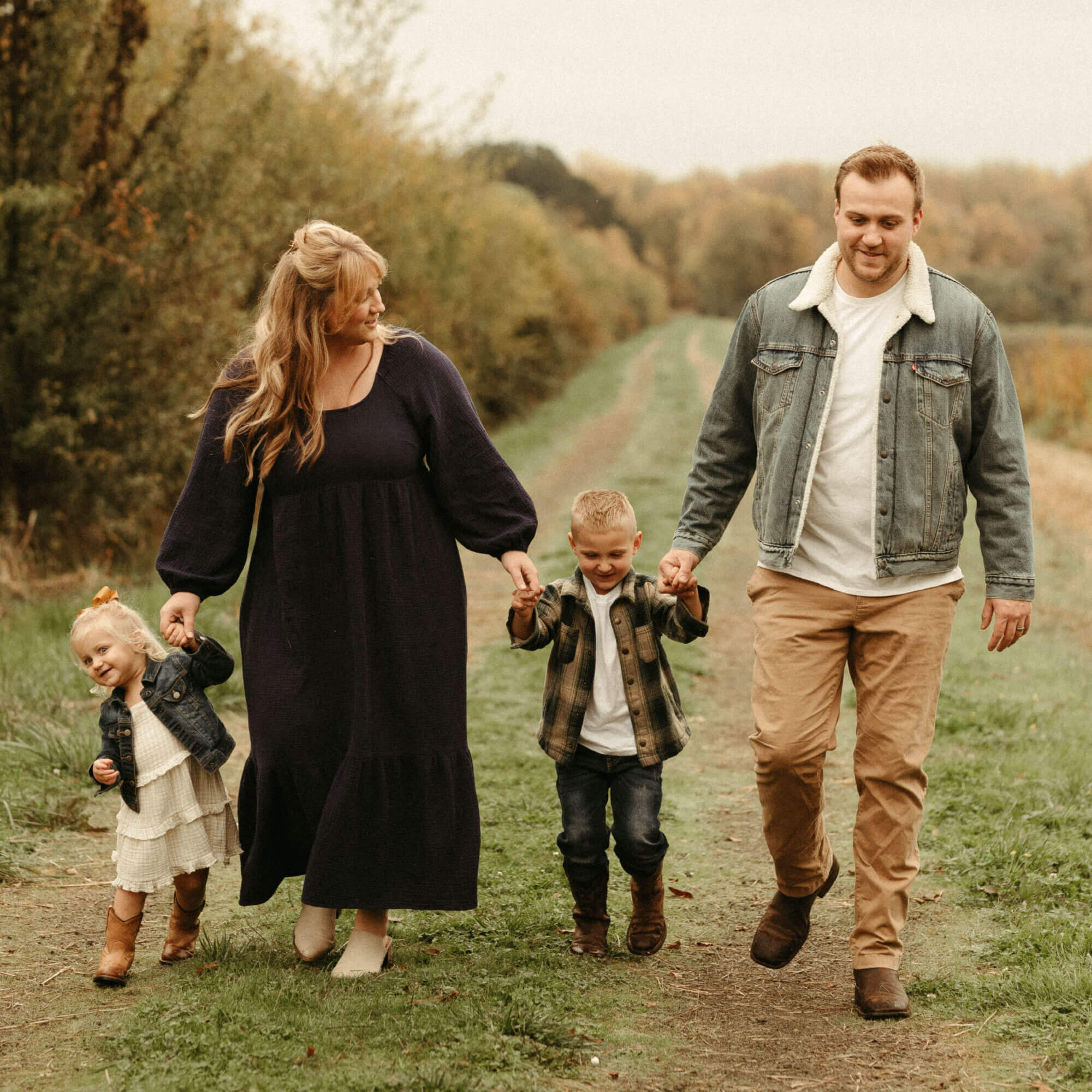 Family of four walking on a trail together during fall.