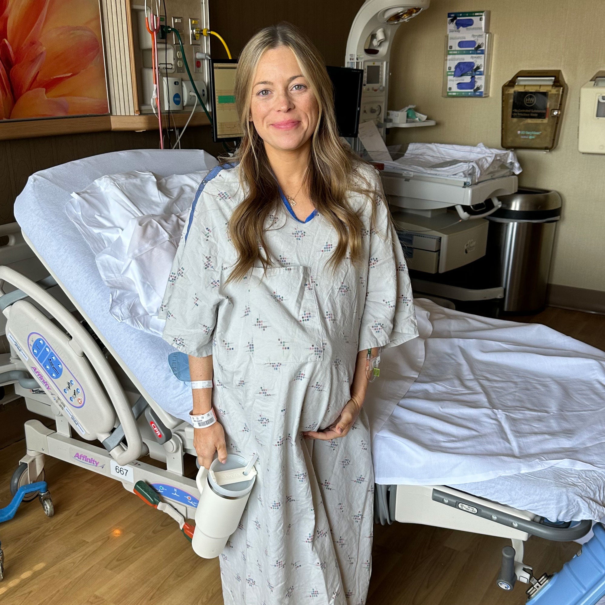 Pregnant woman smiling in hospital gown before giving birth.