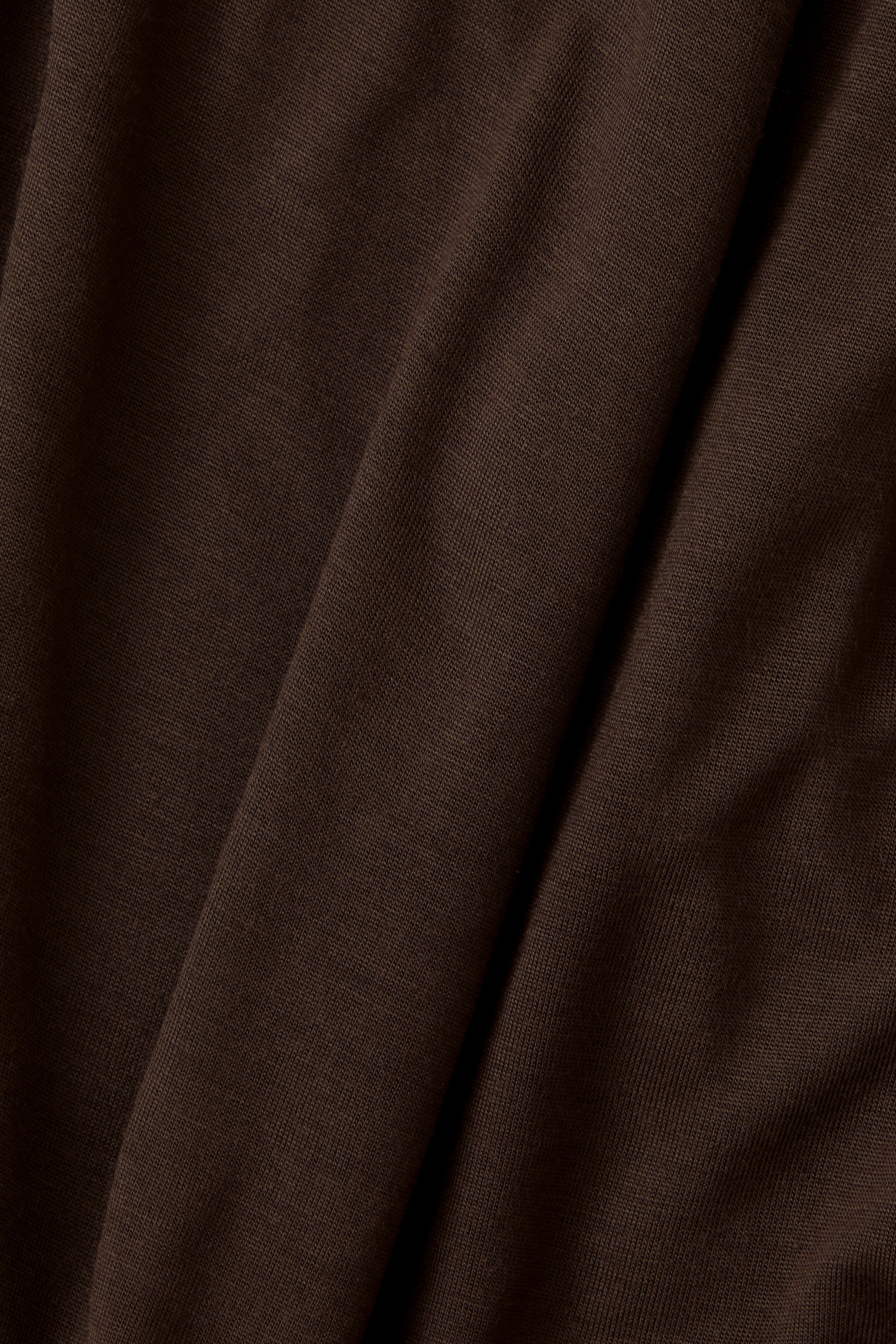 A close-up of draped dark brown fabric with soft folds and a fine knit texture.