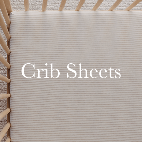 A serene nursery scene featuring a Solly Baby crib sheet in soft, neutral stripes tucked neatly into a wooden crib. Shop Crib Sheets.