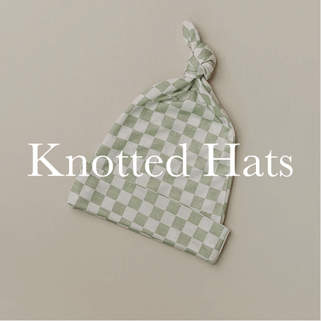 A checkered green and cream knotted hat is laid flat against a neutral backdrop, showcasing its softness and charming design. Shop Knotted Hats.