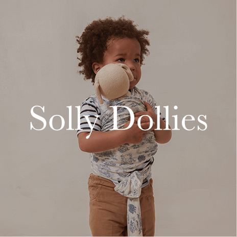 A young child holds a tiny doll wrapped in a mini Solly Baby wrap, mirroring the comfort and bonding of babywearing. Shop Solly Dollies