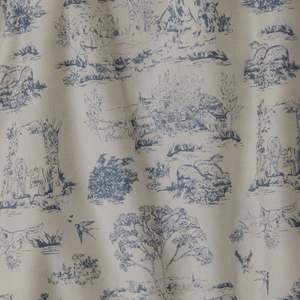 Close-up of Solly Baby's Bleu Toile fabric featuring an intricate blue-on-cream pattern with pastoral scenes of trees, cottages, and animals. A timeless design inspired by vintage elegance.