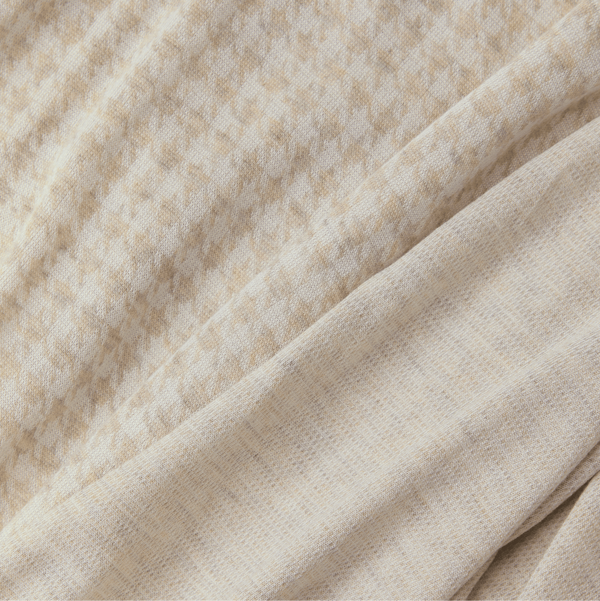 Close-up of beige fabric with a subtle houndstooth pattern