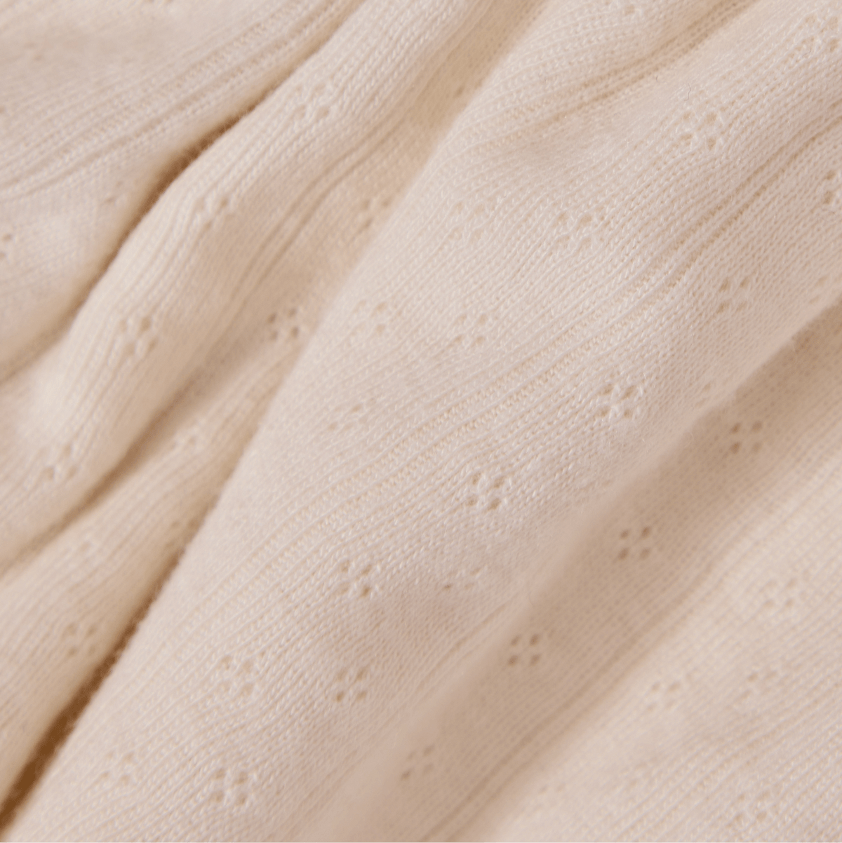 Close-up of beige fabric with a textured pointelle pattern