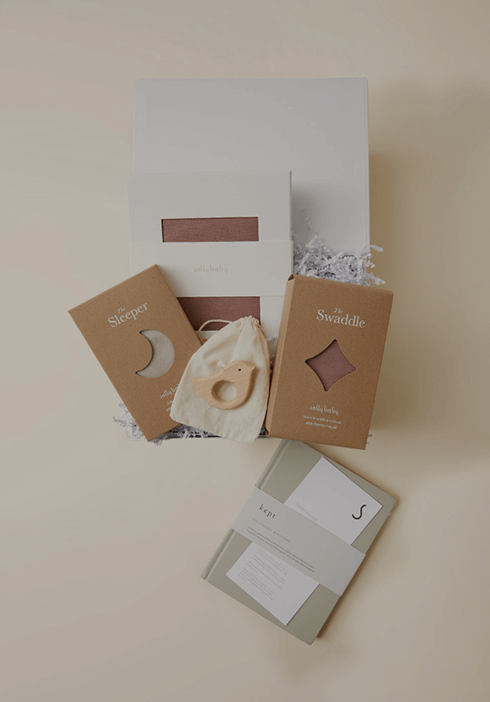 Solly Baby gift set featuring a soft baby sleeper, a swaddle, and a wooden teething ring displayed in elegant packaging. Thoughtful essentials designed for gifting new parents and little ones.