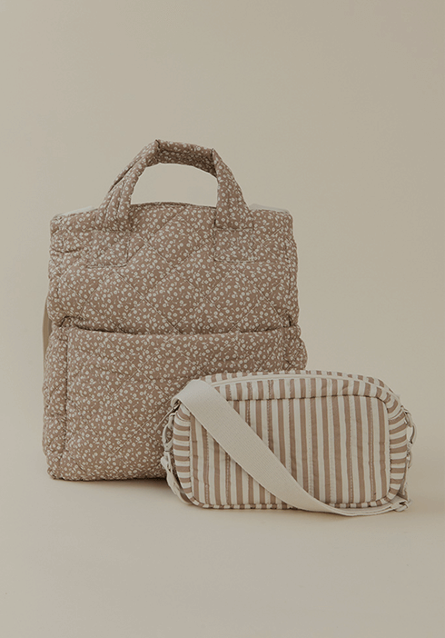 Quilted Solly Baby Totepack in a neutral floral print, displayed alongside a matching striped pouch with an adjustable strap. Stylish, functional storage for everyday essentials.