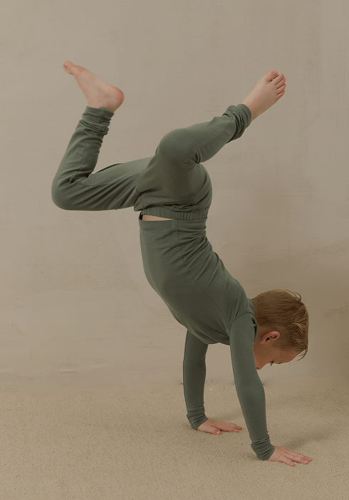 Young boy doing a handstand while wearing Solly Baby pajamas in a deep sage green. Soft, breathable fabric designed for playful days and restful nights.