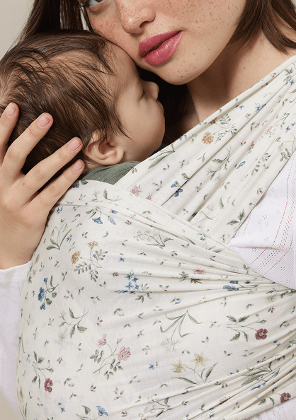 Close up of mom holding baby in a cream wrap carrier with small flower pattern