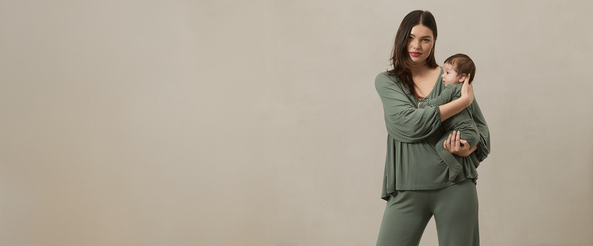 Mother and baby wearing matching green sleep sets in a quiet, cozy moment. Buttery-soft Solly Baby fabric brings ease and comfort to family bedtime routines.