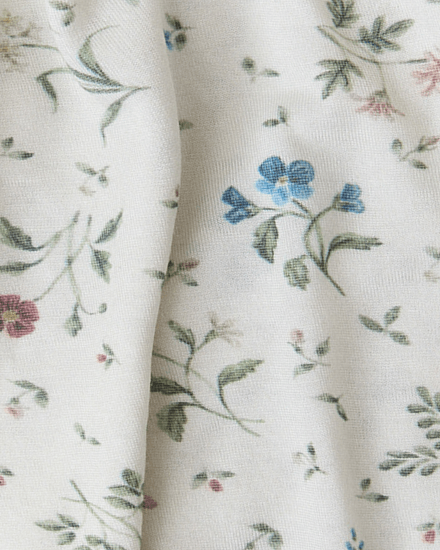 Close up of fabric swatch featuring a cream background and small multi-colored floral print.