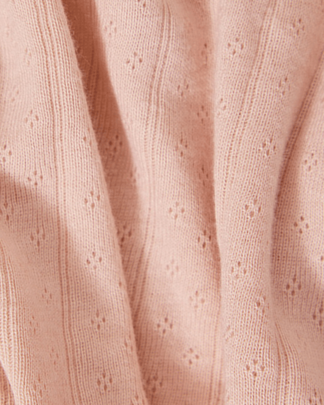 Close up of pink fabric swatch with a pointelle texture. 