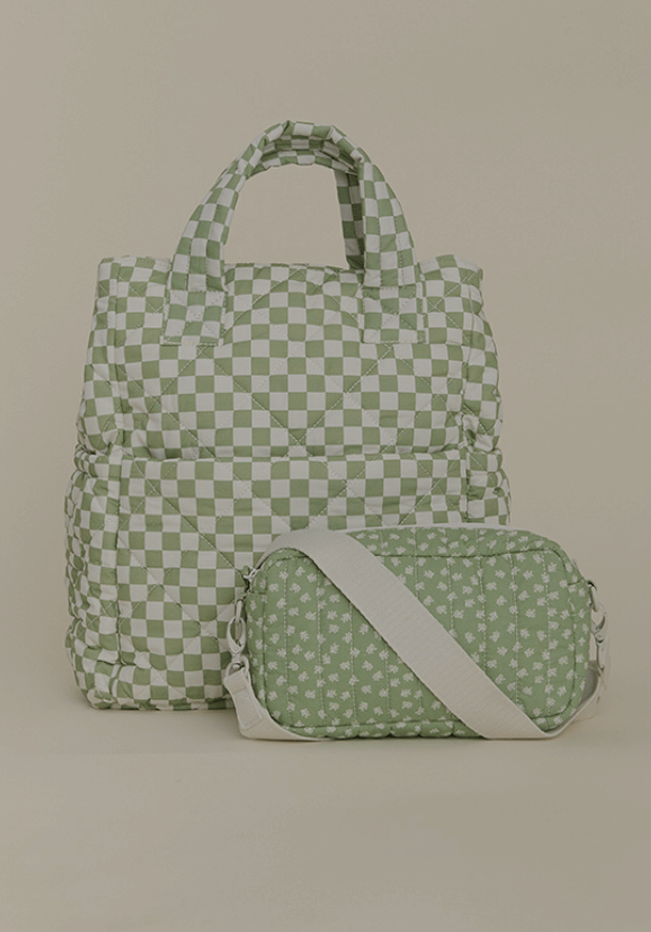 A quilted Totepack in a sage green and cream checkered design stands alongside a matching crossbody bag with a soft green floral print and an ivory strap. Both bags are displayed against a neutral backdrop, highlighting their stylish, functional design for everyday use.