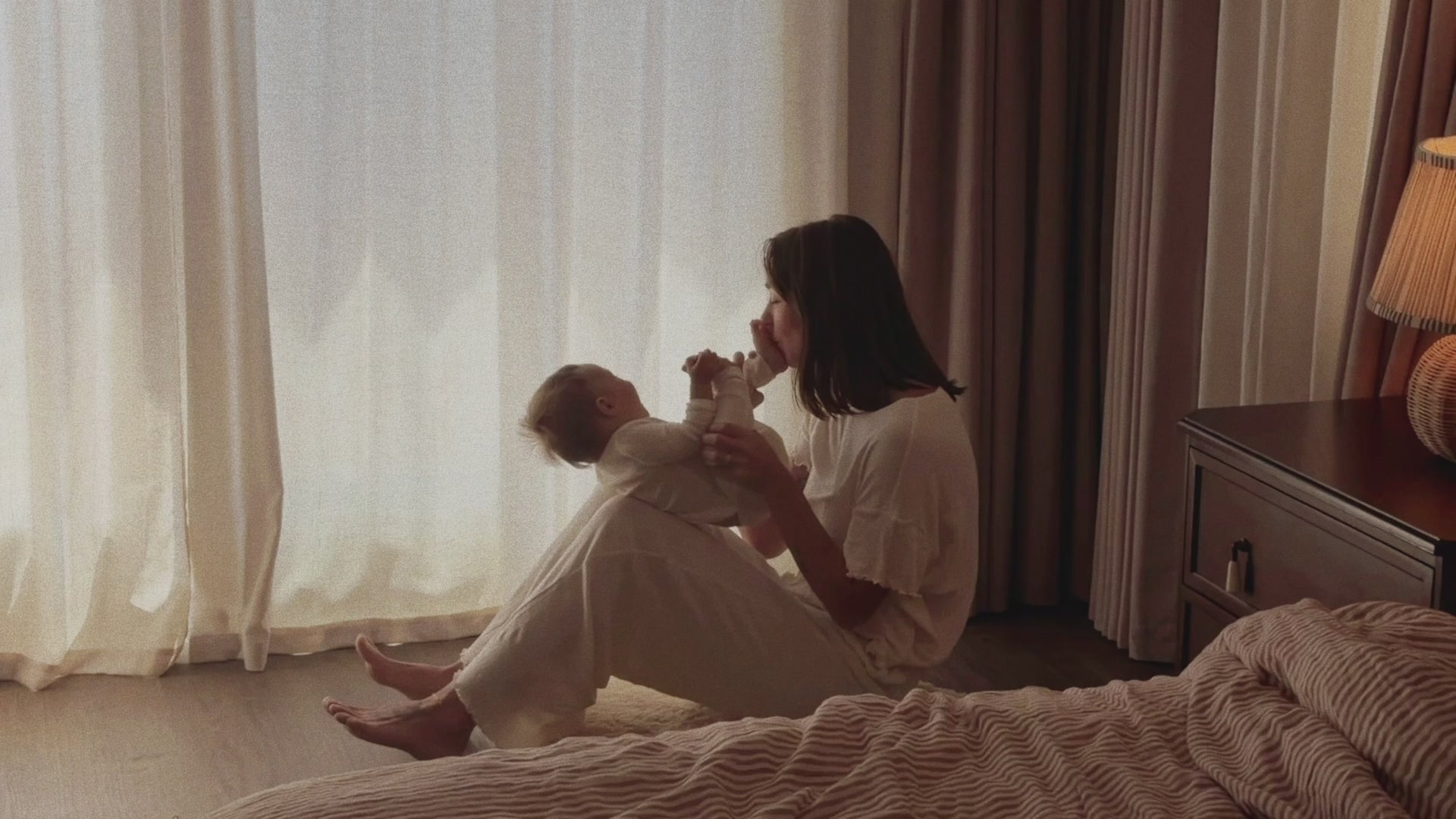 Movie of mom, baby and toddler in white pjs, cuddling and having a cozy morning. 