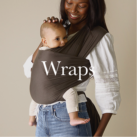 Woman holding a baby in a brown wrap against a beige background
