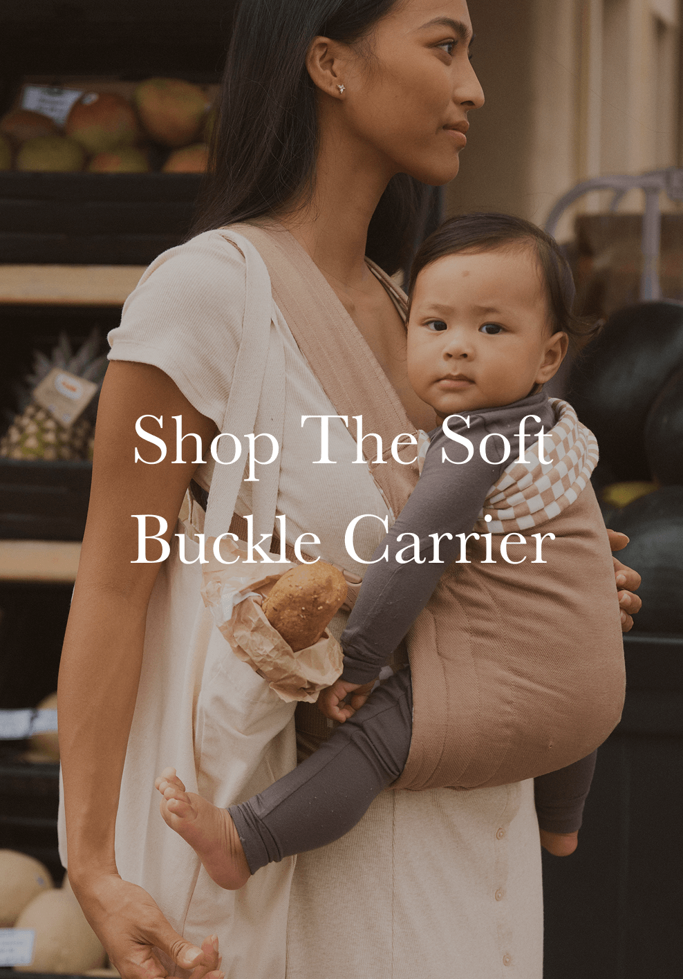 Woman holding a child in a soft buckle carrier with text overlay.