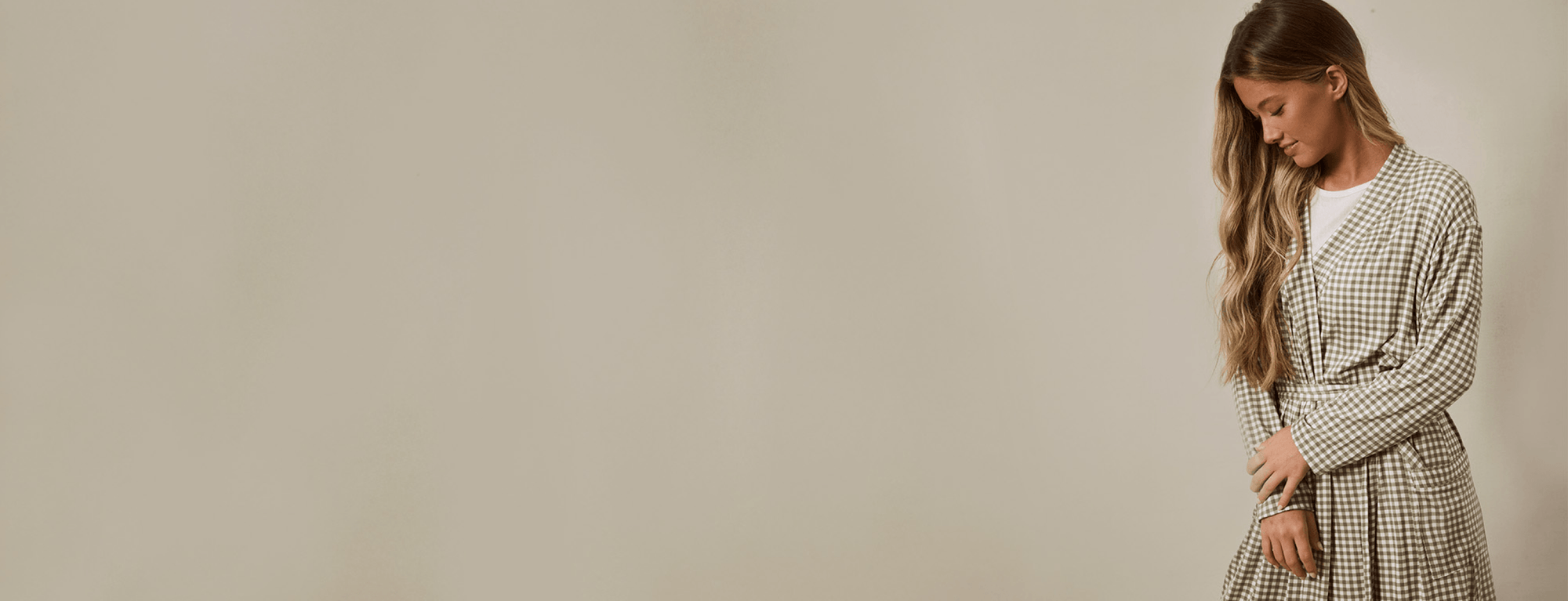 Woman wearing a green gingham robe against a plain background