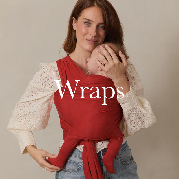 Mom wearing a baby in a vibrant red Solly Baby Wrap, paired with a white lace blouse and jeans. Shop Wraps. 