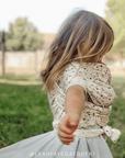 Child wearing a floral dress outdoors wearing strawberry solly dolly wrap for play.