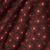 A close-up of draped fabric with an allover floral pattern. The design features dark red flowers with light pink centers on a dark brown background.