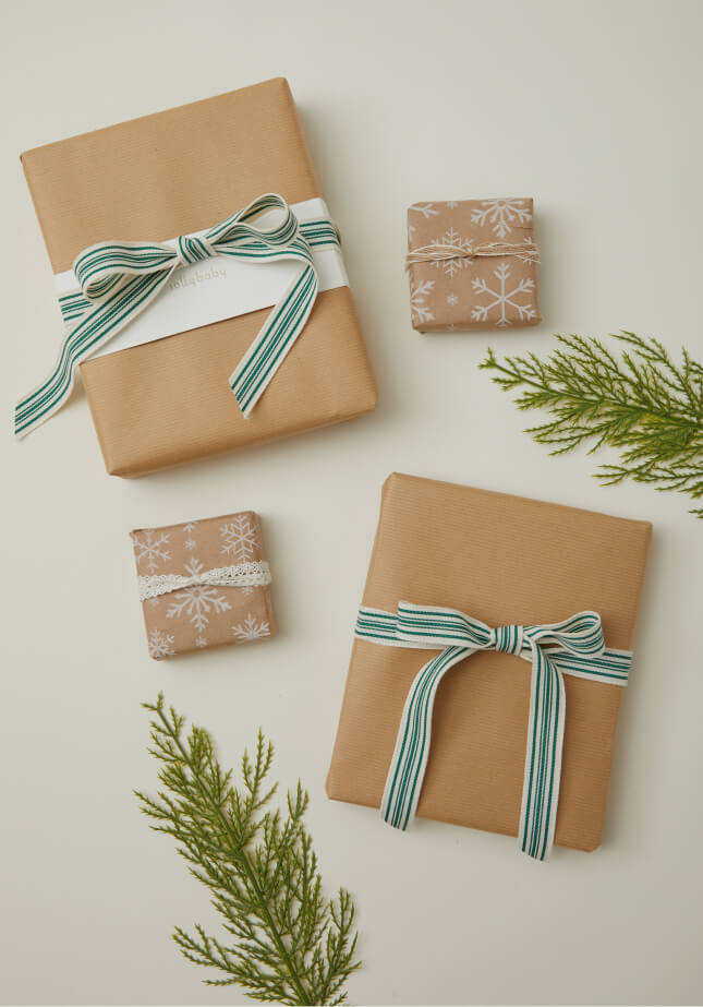 Festive holiday gifts wrapped with green-striped and lace ribbons, decorated with fresh evergreens.