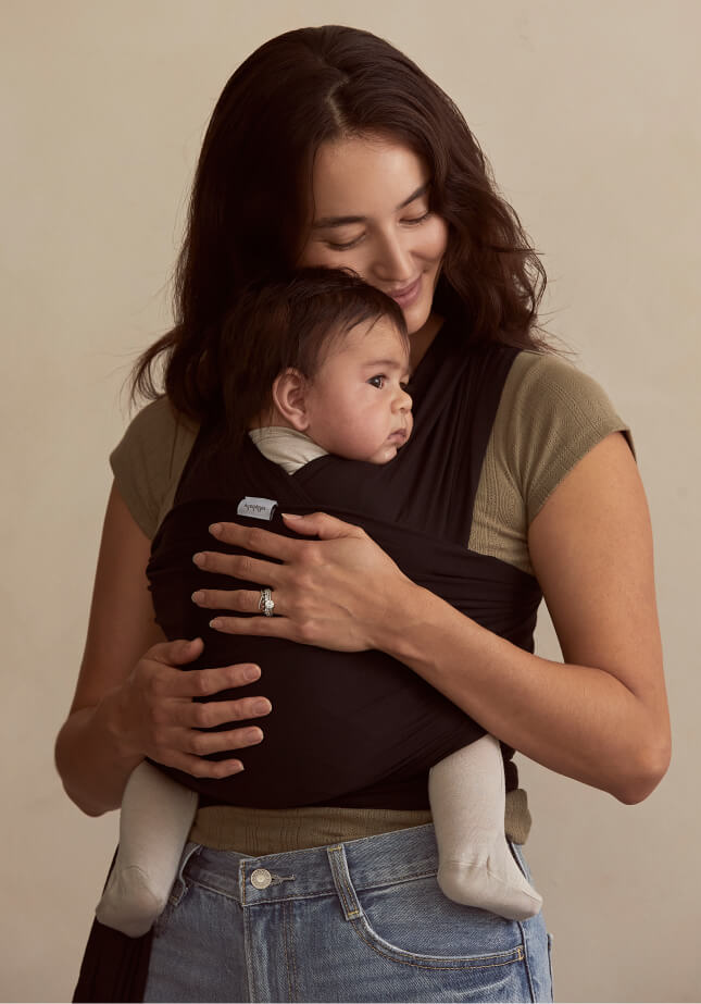 A mother standing while holding her baby in a Black Solly Baby Wrap.