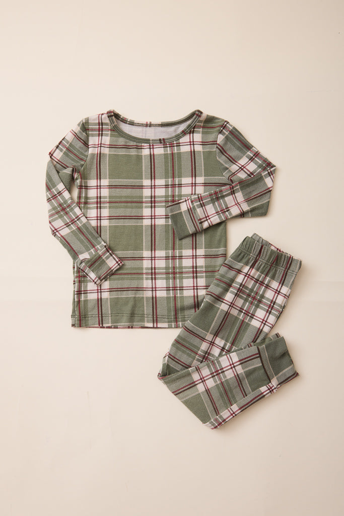 A two-piece long-sleeve pajama set featuring a green, white, and red plaid pattern, laid flat on a light beige background.
