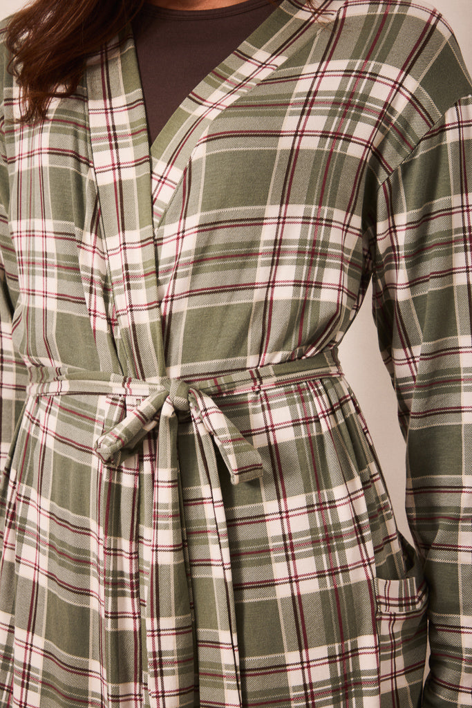 A close-up of a plaid wrap-style top or robe with a tie waist, featuring green, white, and burgundy lines over a dark brown undershirt.