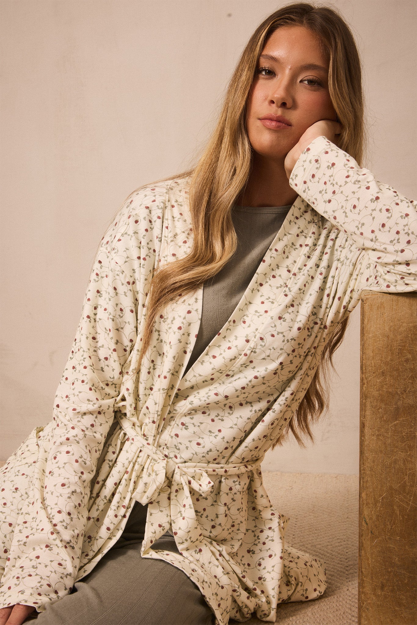Woman wearing a strawberry patterned robe against a beige background