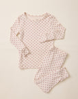 A two-piece baby pajama set featuring a long-sleeve top and matching pants in a soft cream fabric with a small red star pattern, laid flat on a light beige background.