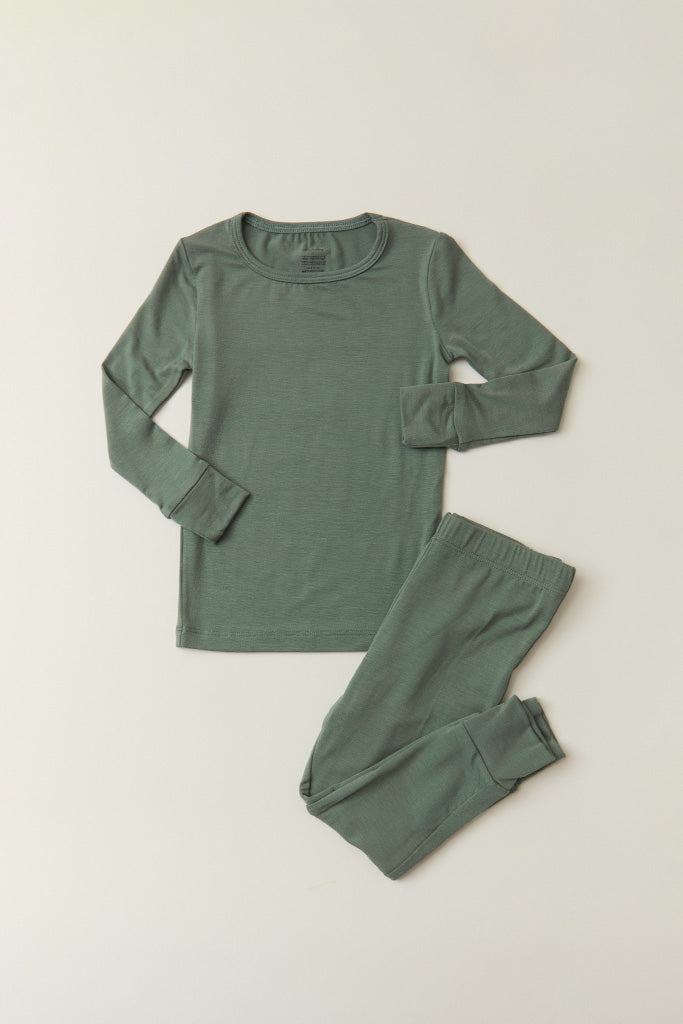 A two-piece long-sleeve pajama set in a muted sage green color, laid flat on a light beige background. The set includes a crewneck top and matching pants.
