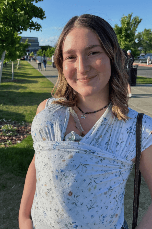 Woman with a baby in floral baby wrap carrier outdoors on a sunny day