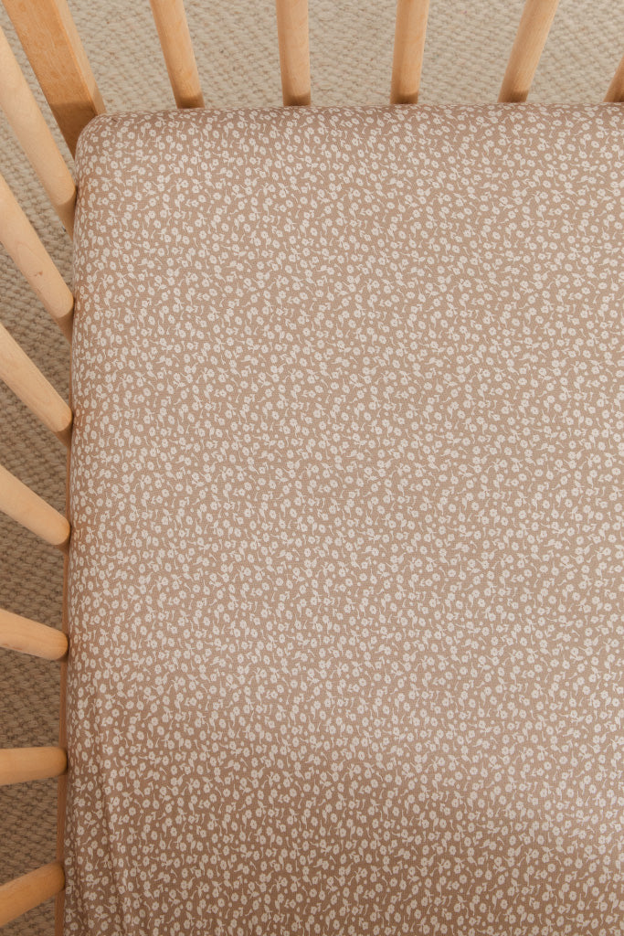 A close-up image of a Solly Baby Crib Sheet in the Cream Floral print featuring petite cream buds gently scattered atop a soft taupe brown base. 