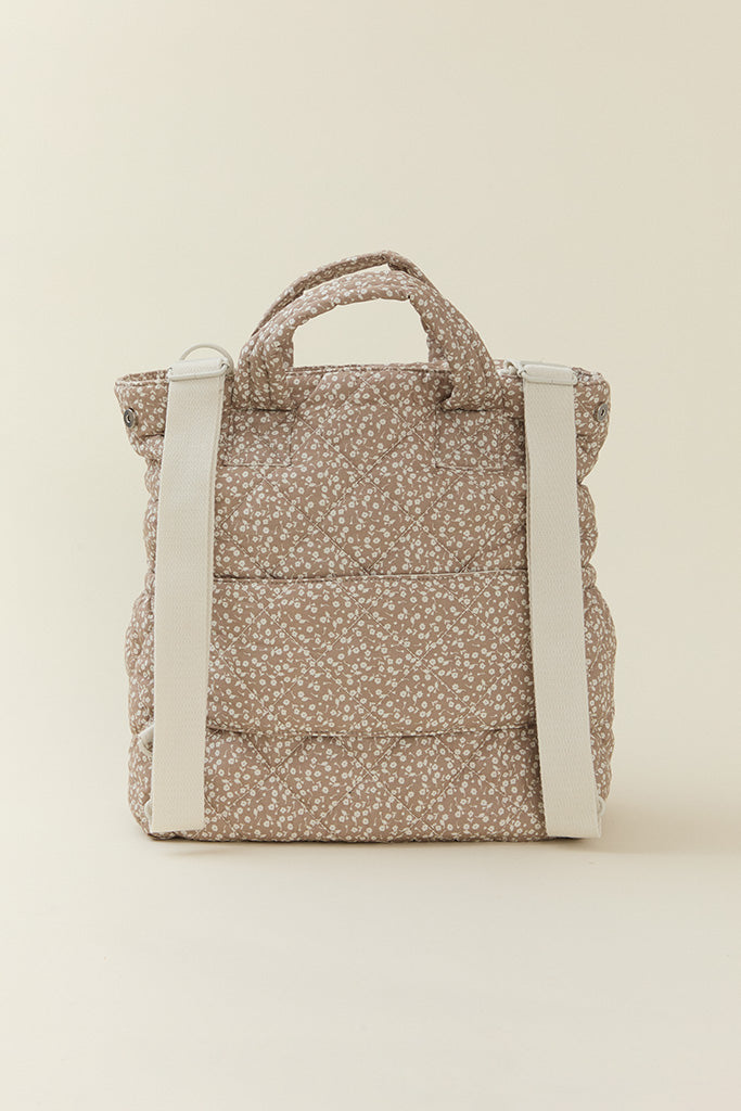 Back view of Solly Baby Totepack in cream floral design, highlighting quilted texture and adjustable white backpack straps.