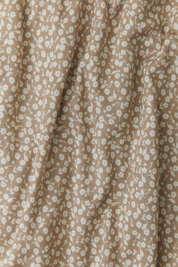 A close-up fabric shot of Solly Baby&#39;s Cream Floral print, featuring delicate cream florals on top of a taupe background. 