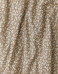 A close-up fabric shot of Solly Baby's Cream Floral print, featuring delicate cream flowers on top of a taupe background.  