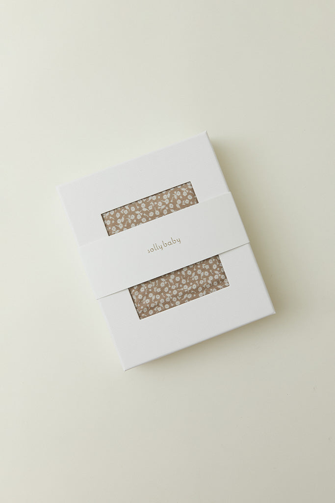  A product packaging shot of the Solly Baby Wrap in a white box with a window showing the Cream Floral print inside.