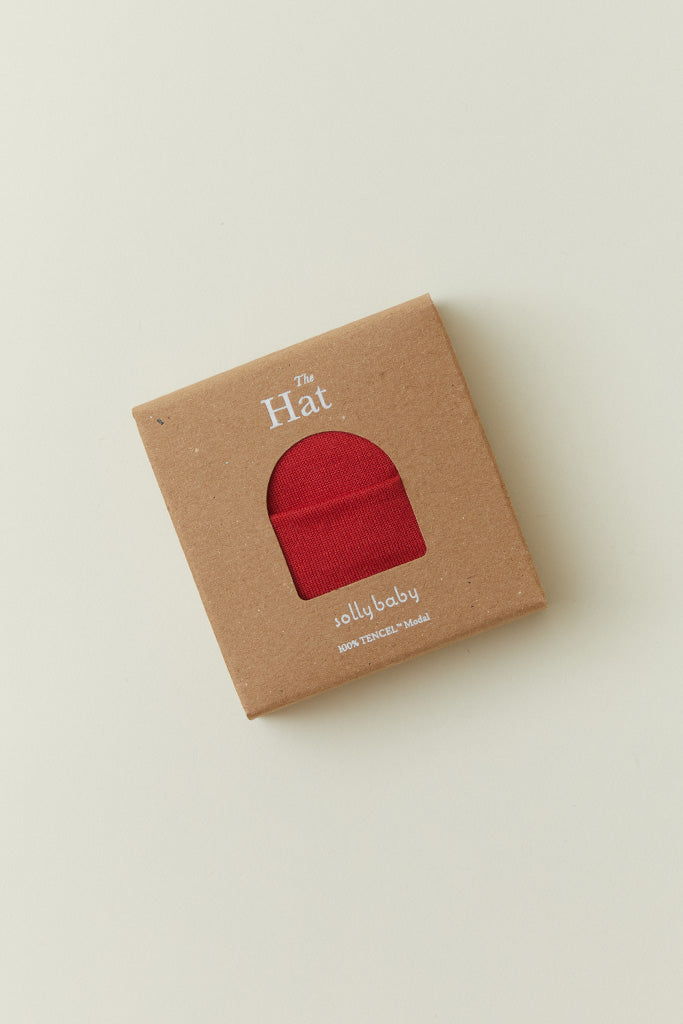 A product packaging shot of the Solly Baby Knotted Hat in a box with a window showing the Currant colorway inside. 