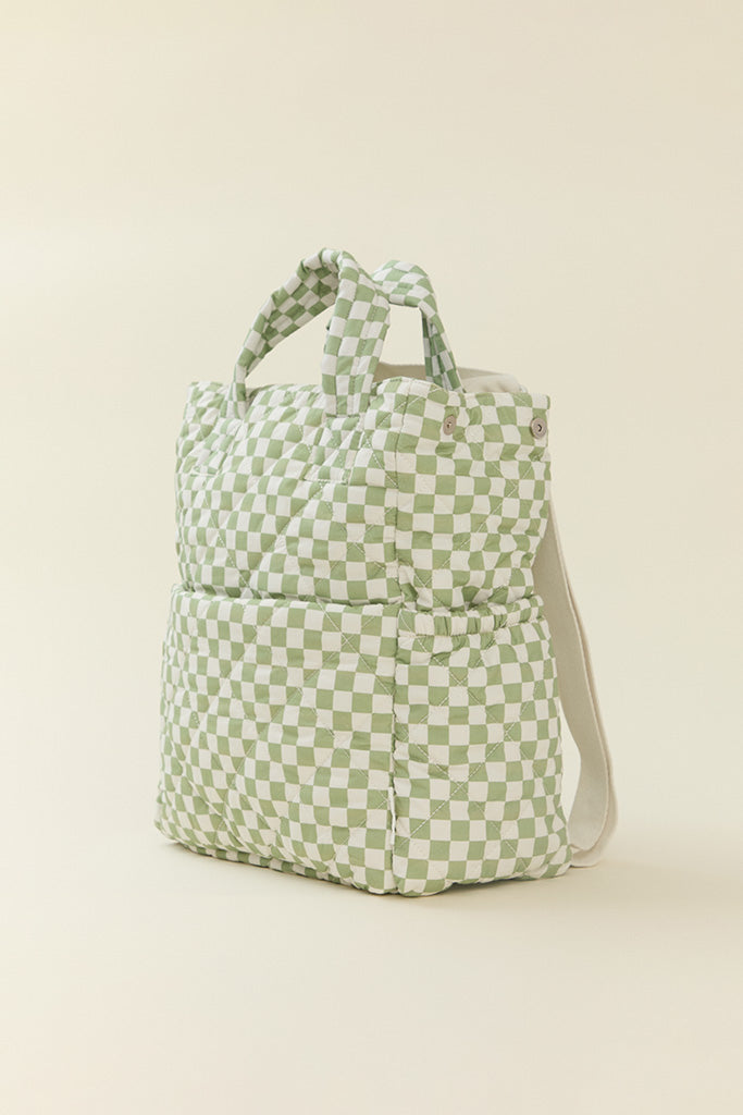 A side view of Solly Baby Fern Chequer Totepack showcasing its quilted fabric and structured shape in  a soft green and cream checkered print.