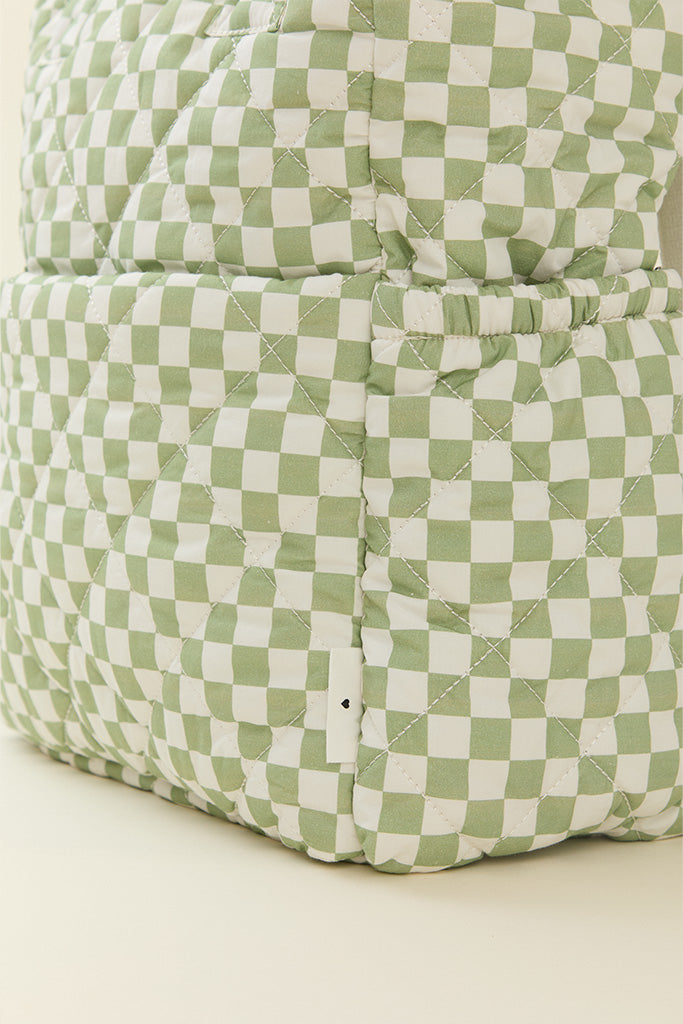 A close-up image of the side detailing on Solly Baby Fern Chequer Totepack diaper bag, including a front-pocket sleeve and water bottle pocket.