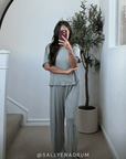 Woman taking a mirror selfie wearing a mist pointelle sleep set in a room with a plant and staircase with text overlay