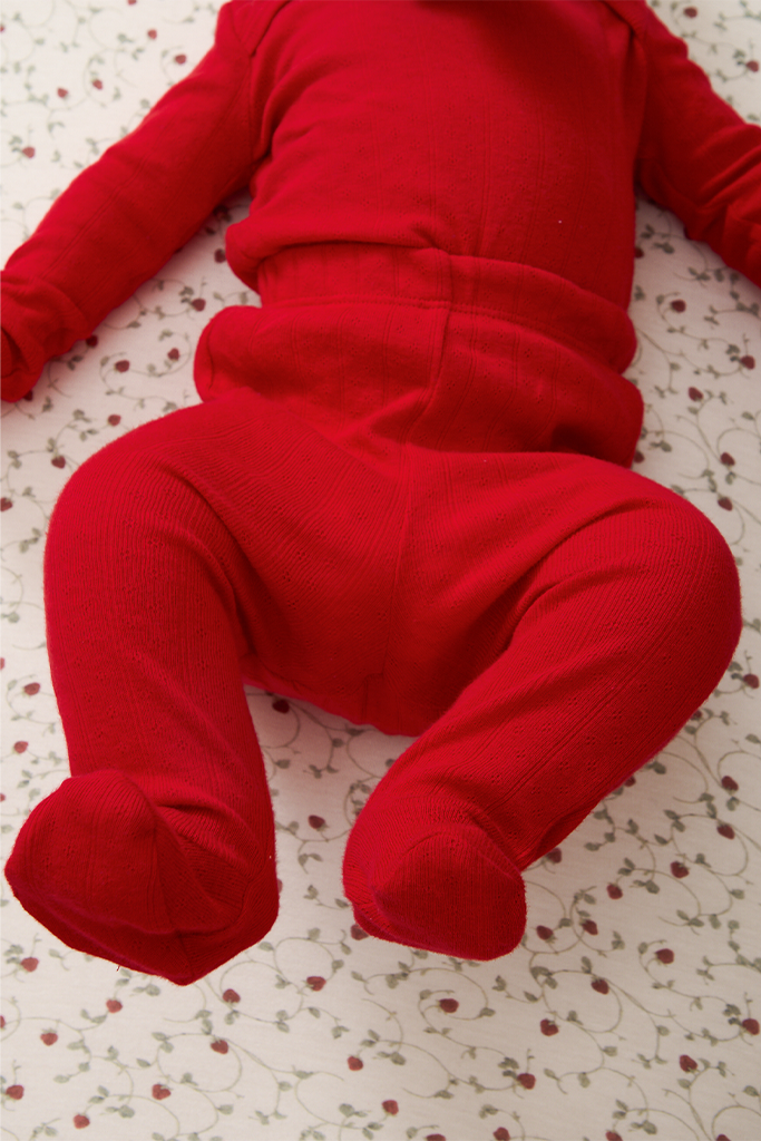 Red pointelle baby sleep set on a strawberry-patterned surface
