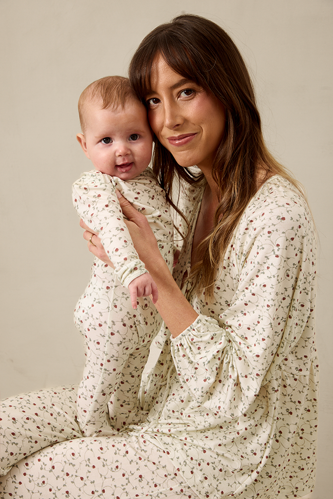 Woman and baby wearing matching pajamas against a plain background