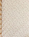 Top view of a crib sheet with a dainty hand-painted strawberry vine print.