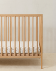 Wooden crib with crib sheet in strawberry print, featuring a delicate hand-painted strawberry vine on a soft neutral background.
