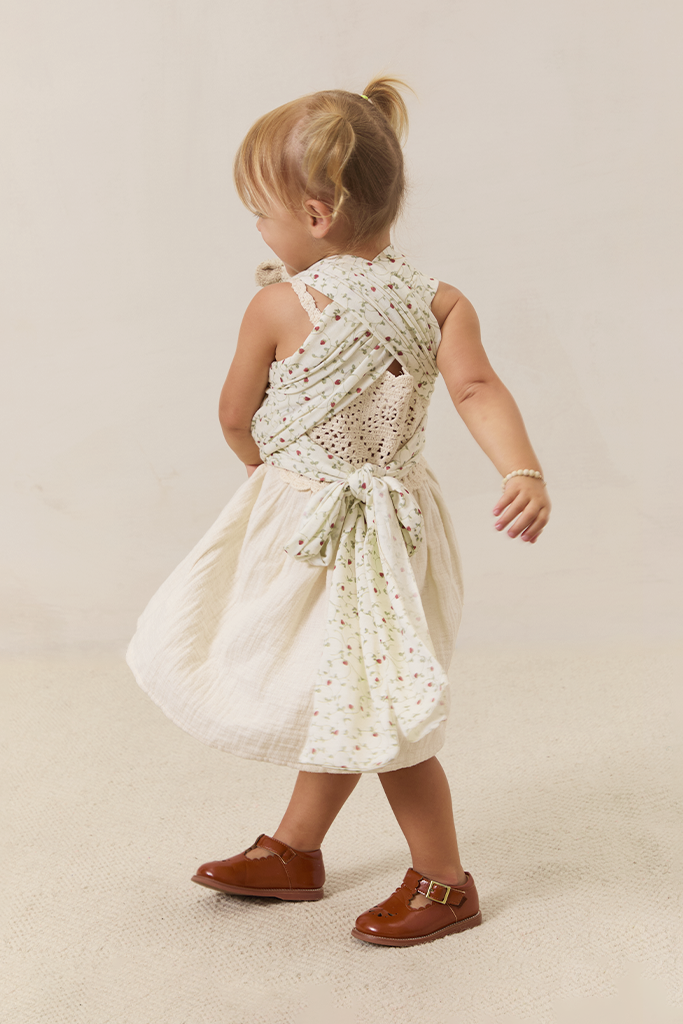 Child wearing a white dress wearing solly dolly with strawberries on it on a beige background