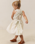 Child wearing a white dress wearing solly dolly with strawberries on it on a beige background